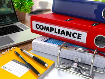 Pile of files and paperwork on a desk for compliance documentation