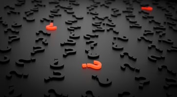many black questions marks laid out on a table with two highlighted in red