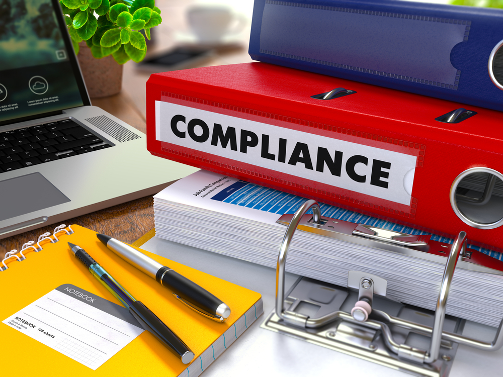 Pile of files and paperwork on a desk for compliance documentation
